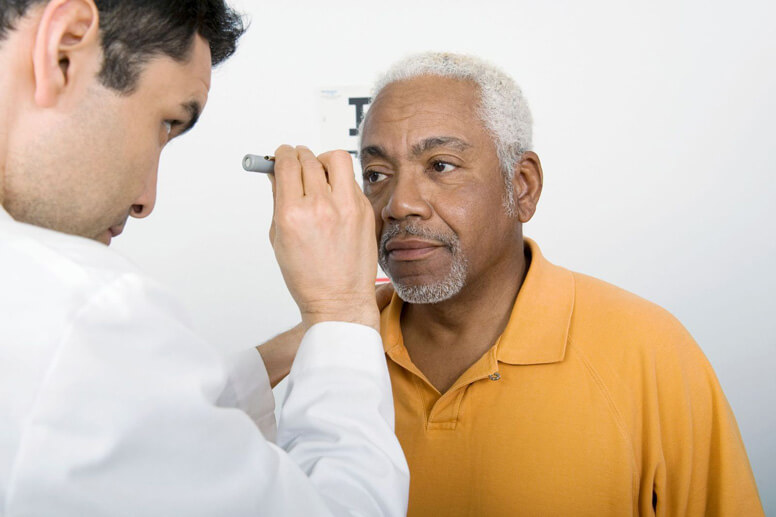 eye doctor looking into male patient's eye